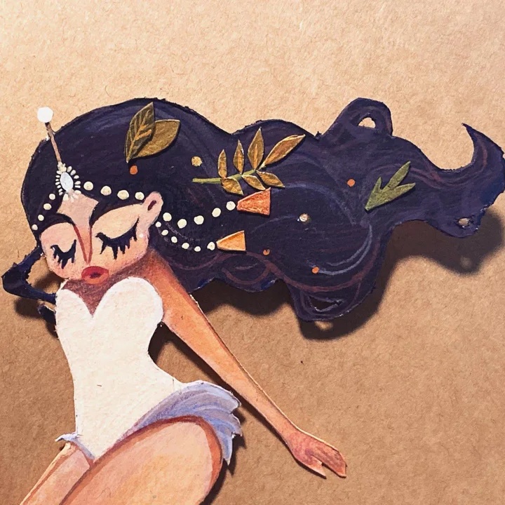 Painted paper cut-out of a dancer in a white bodice, eyes closed, her long dark hair strung with pearls and leaves.