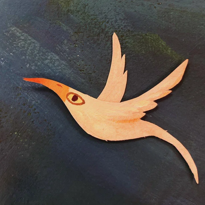 Painted paper cut-out of a peach-colored bird with a long beak and swept-back wings on a dark background.