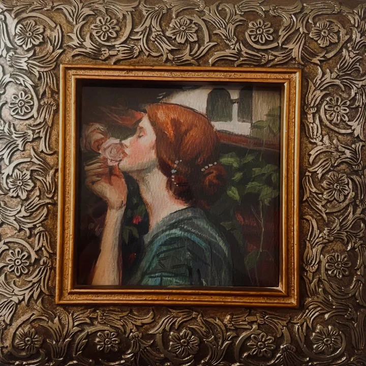 Painting of a red-haired woman in a green dress smelling a rose, after Waterhouse, shown in an ornate silver frame.