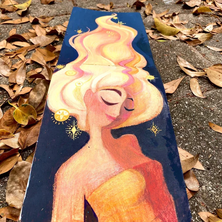 Painting on a long wood plank of a woman with closed eyes and flame-like white-gold hair rising against a starry navy sky.