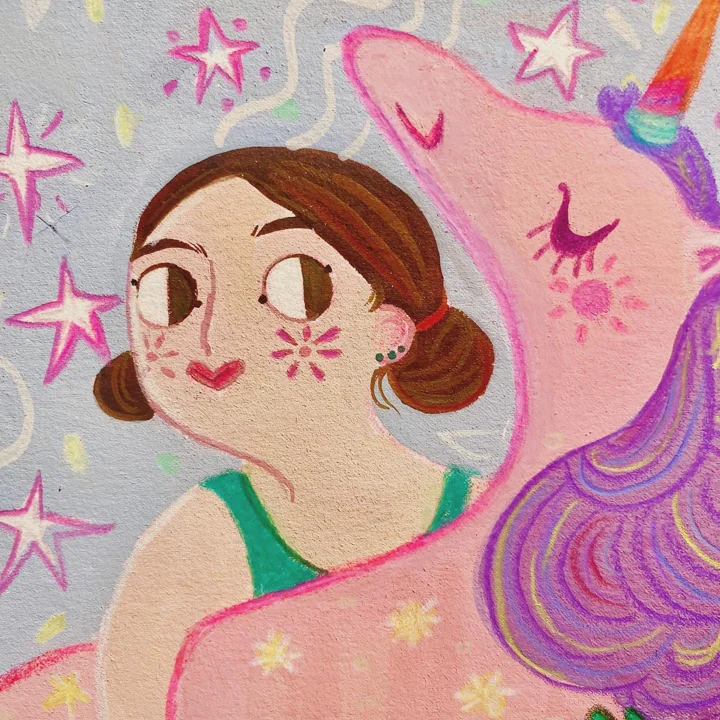 Painted mural detail of a girl with hair buns and cheek markings beside a pink unicorn with a rainbow horn, among stars.