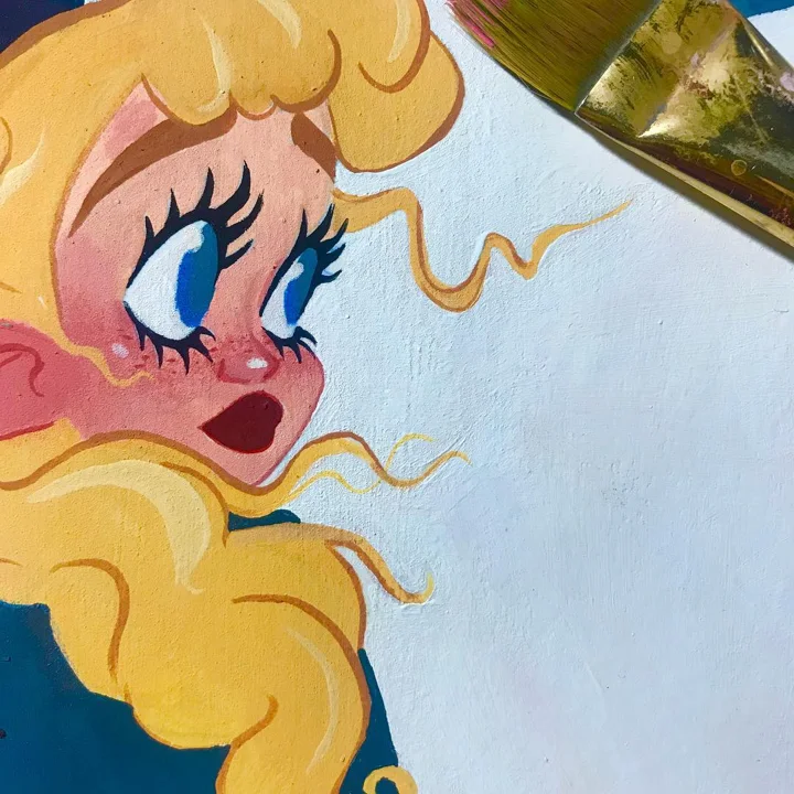 Painting in progress of a cartoon girl with curly blonde hair and big blue eyes, a paintbrush resting at the edge.